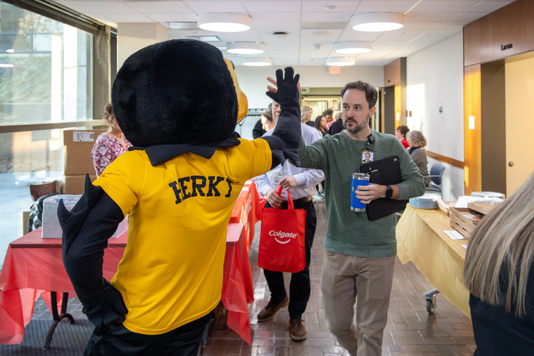 Dr. Geneser gives a high-five to Herky ahead of research day.